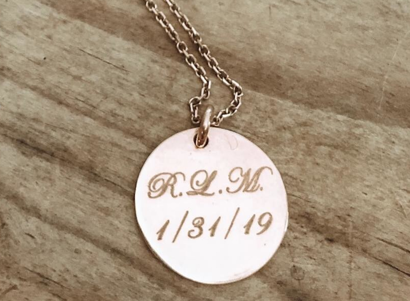 gold round pendant engraved with significant date