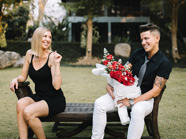 Karrie and Casey joke around with flowers on a bench.