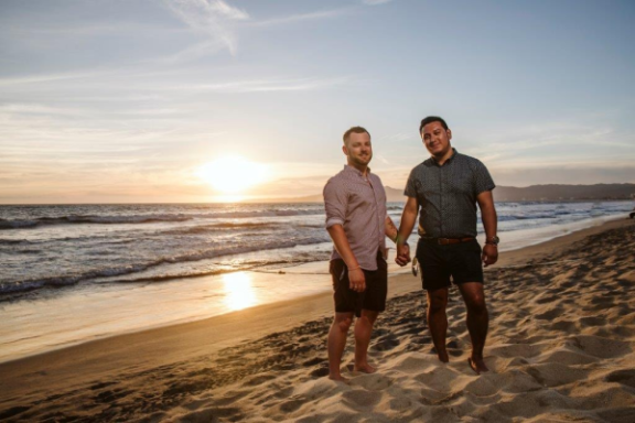 Andrew and Brian holding hands on the beach.