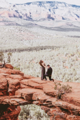 Man proposes to woman on red rock structure.