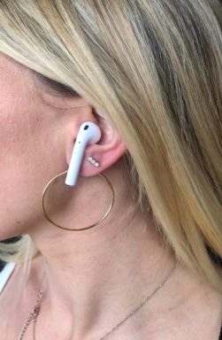 Woman wearing gold hoops with airPods.