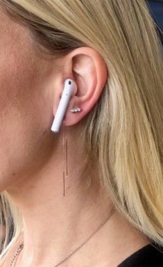 Woman wearing threader earrings with AirPods.