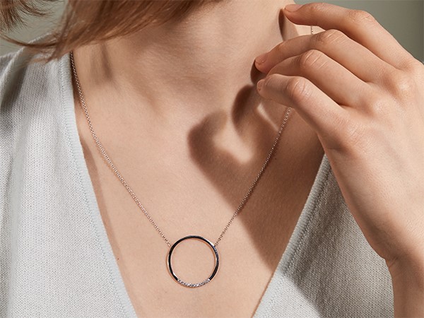 Woman wearing diamond circle necklace.
