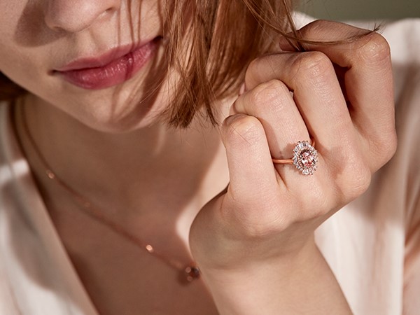 Woman wearing pink sapphire engagement ring.