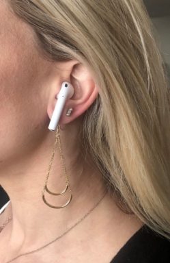 Woman wearing yellow gold dangles with airPods.