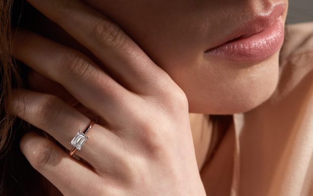 Woman wearing east-west set emerald cut diamond engagement ring.