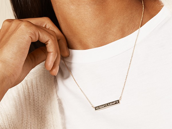 Coordinates engraved on gold bar necklace.