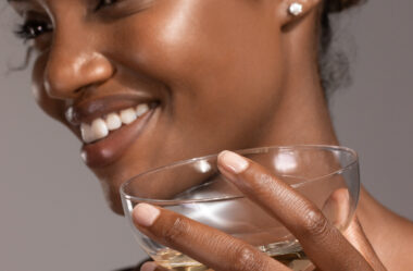 Woman holding a glass smiling wearing diamond stud earrings