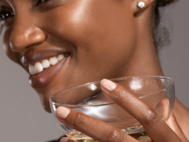 Woman holding a glass smiling wearing diamond stud earrings