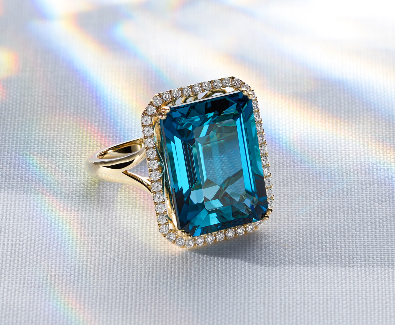 Nascha London Blue Topaz & Diamond Halo Ring A natural diamond halo beautifully frames the natural London blue topaz gemstone at the center of this vibrant cocktail ring. Crafted in warm 14-karat yellow gold, it features filigree detailing around the sides for an ornate finishing touch.