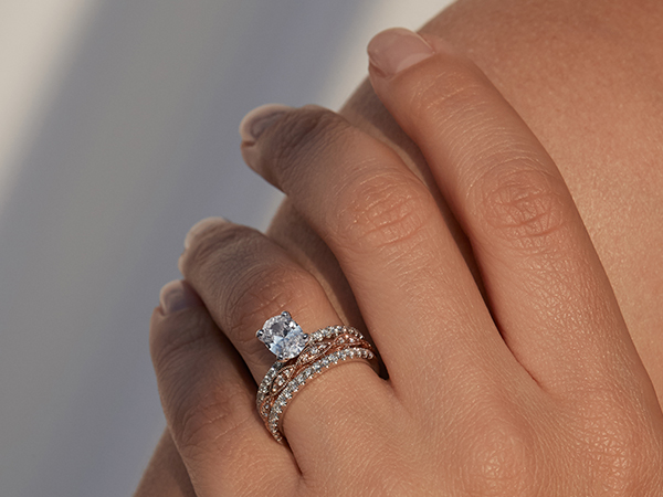 Woman wearing an oval engagement ring and wedding band stack.