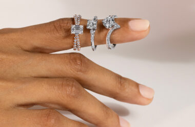 The image you sent me shows a close-up of a woman’s left hand wearing three rings. The rings are all on the ring finger. The ring closest to her knuckle is a split, rose gold band with a textured surface. The middle ring is a thin, platinum band set with a single diamond. The ring closest to her fingertip is a thicker band made of white gold. It has a large, round gemstone in the center that could be a diamond or another clear stone.