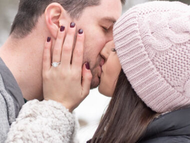 man and woman kissing after winter proposal.
