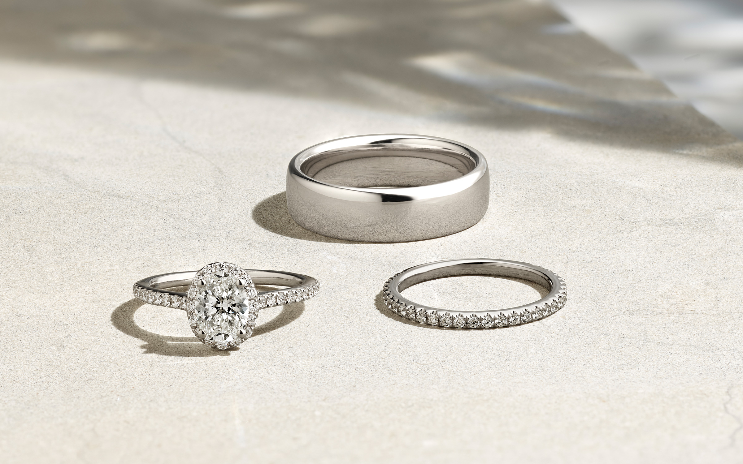 A diamond engagement ring, diamond wedding band, and men's wedding band,