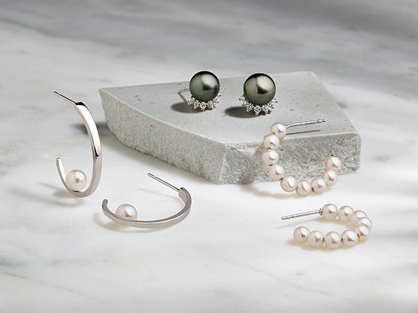 an assortment of Pearl earrings.  pearl studs with diamond halos, pearl hoops