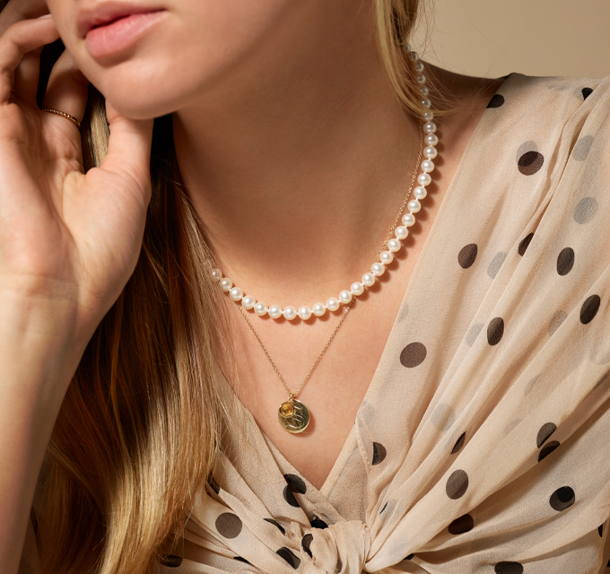woman wearing pearl necklace along with a zodiaz charm