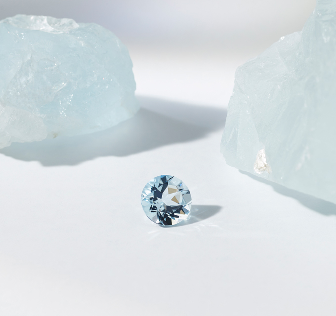 raw aquamarine stone with round cut and polished aquamarine stone to show it's transformation