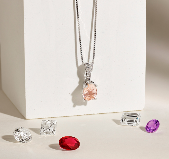 image of gemstone pendant with loose gemstones around it, diamond and ruby