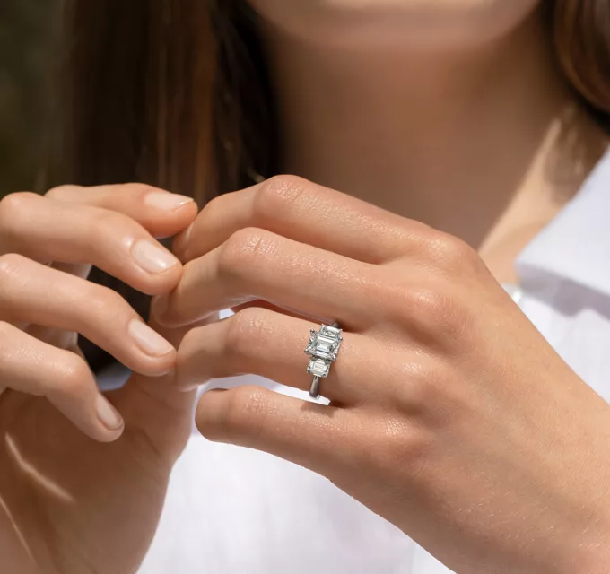 woman wearing a three-stone emerald cut diamond ring in white gold