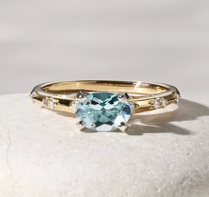 oval aquamarine center stone engagement ring with accent diamonds in a yellow gold ring