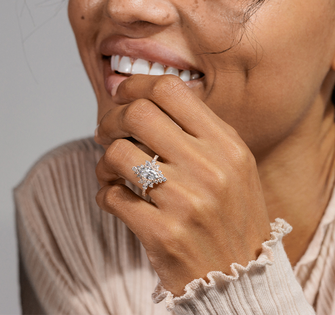 woman wearing vintage engagement ring, the ring has marquise cut diamonds around the diamond center stone