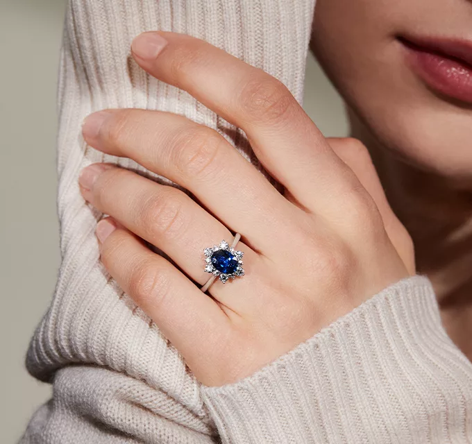 woman wearing an oval halo engagement ring with blue sapphire center stone