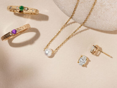 stackable gemstone rings, single pearl necklace, and oval diamond studs. all in gold