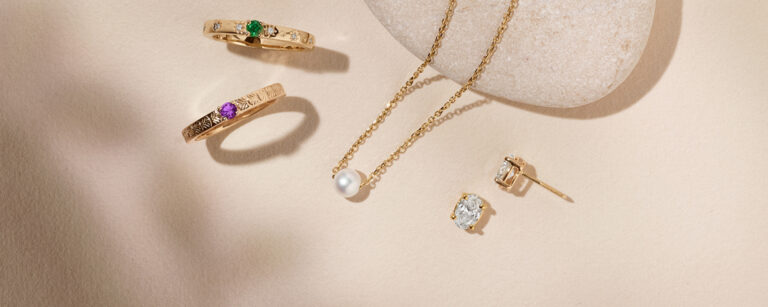 stackable gemstone rings, single pearl necklace, and oval diamond studs. all in gold