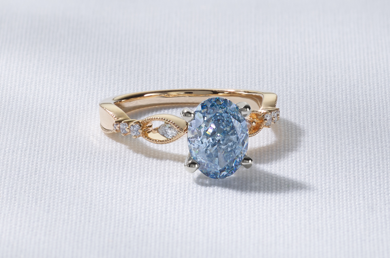 An oval cut fancy blue lab-grown diamond set in a gold ring