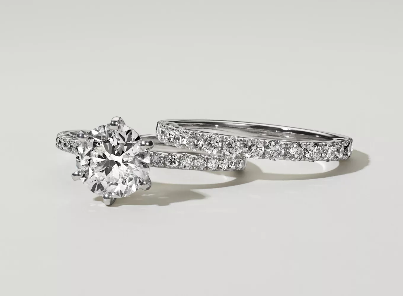 Matching wedding ring set featuring a round center stone in white gold. A pave engagement ring and pave wedding band set