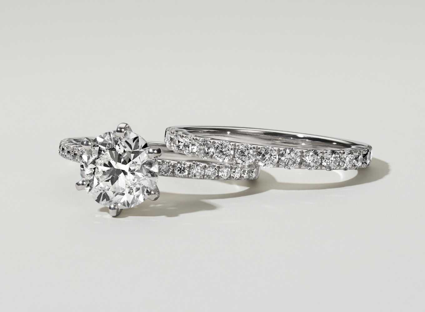 Matching wedding ring set featuring a round center stone in white gold. A pave engagement ring and pave wedding band set