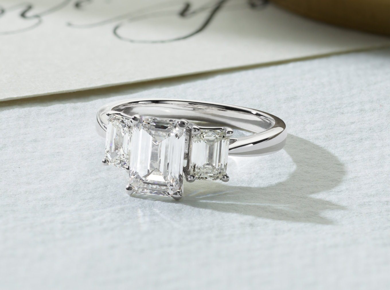 Gatsby Three-Stone Engagement Ring
Two stunning emerald cut natural diamonds accent the center stone of your choice in this classic three-stone design. Crafted in bright 14-karat white gold, this timeless engagement ring will sparkle for years to come. For more information on selecting your center stone, Live Chat online, call a customer service representative at 1-866-467-4263, or visit one of our store locations.