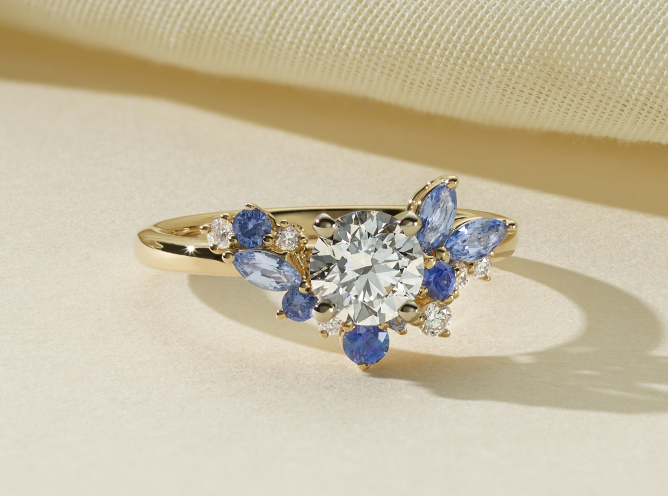 Yasmin Blue Sapphire Engagement Ring A beautiful array of natural sapphire accents in varying shapes and shades of blue gives a floral look in this 14-karat yellow gold engagement ring. It also features natural diamond accents for a touch of sparkle. Add the center stone of your choice to complete this dreamy design. For more information on selecting your center stone, live chat online, call a customer service representative at 1-866-467-4263, or visit one of our store locations.