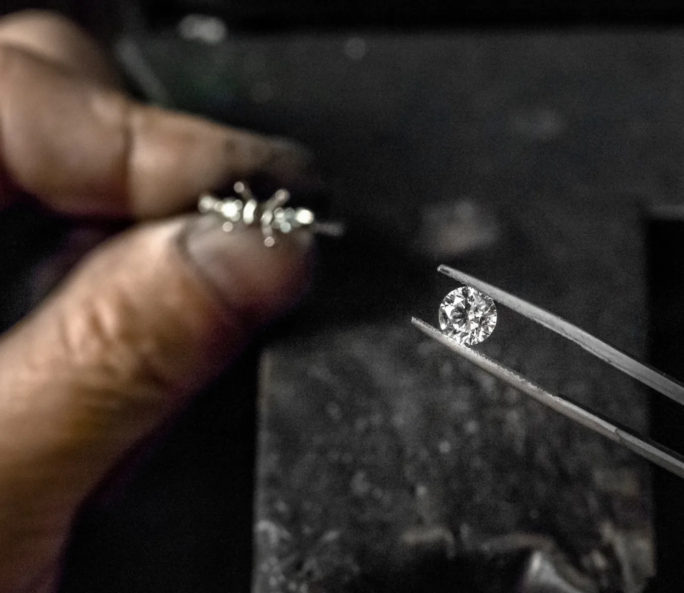 jeweler setting a diamond center stone into a gold engagement ring