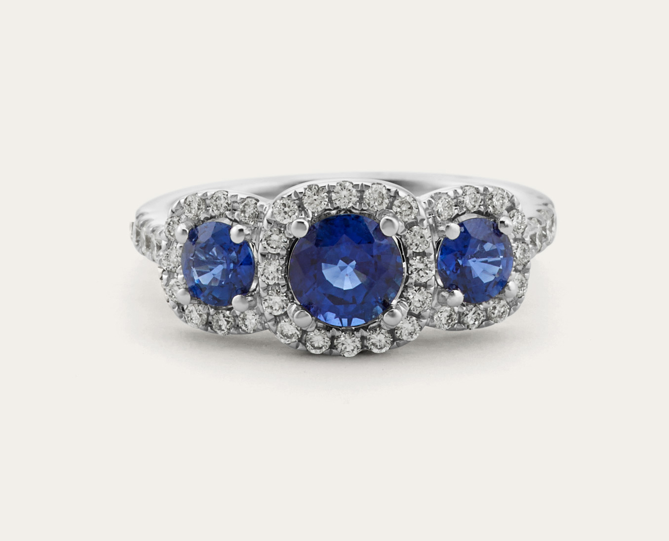 Capri Three-Stone Sapphire & Diamond Ring Each natural sapphire in this stunning three-stone ring has its own sparkling halo of natural diamonds. Crafted in bright 14-karat white gold, this ring has beautiful hidden details with swirled milgrain and an additional natural sapphire accent visible along the profile.