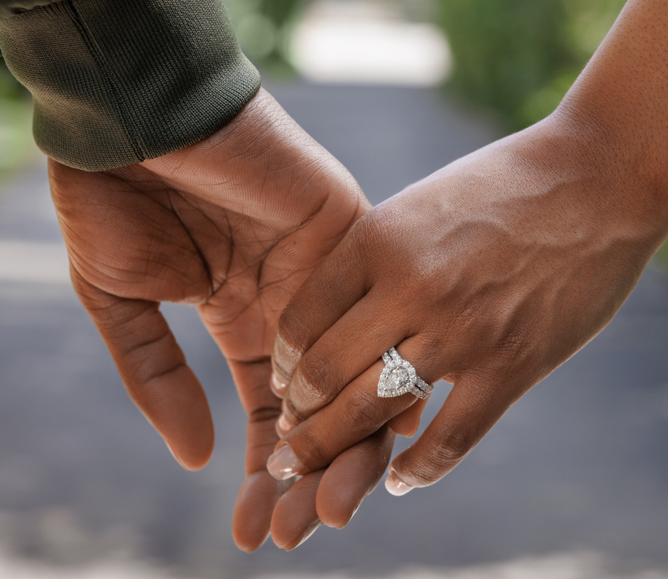 Close up of man and woman holding hands, highlighting her new engagement ring