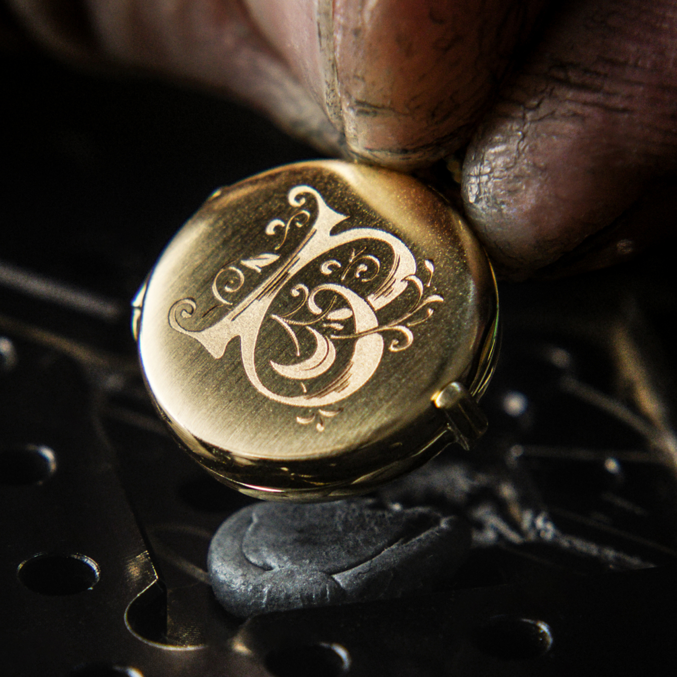 jeweler finishing an ornate engraving of a B on a gold locket
