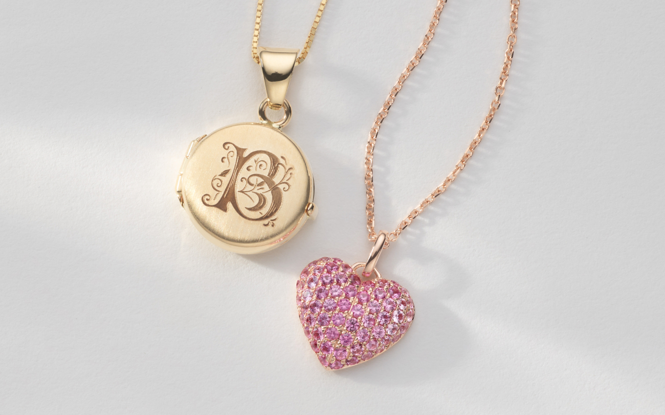 two pendant necklaces, on featuring an engraved letter B and the other a pink sapphire heart