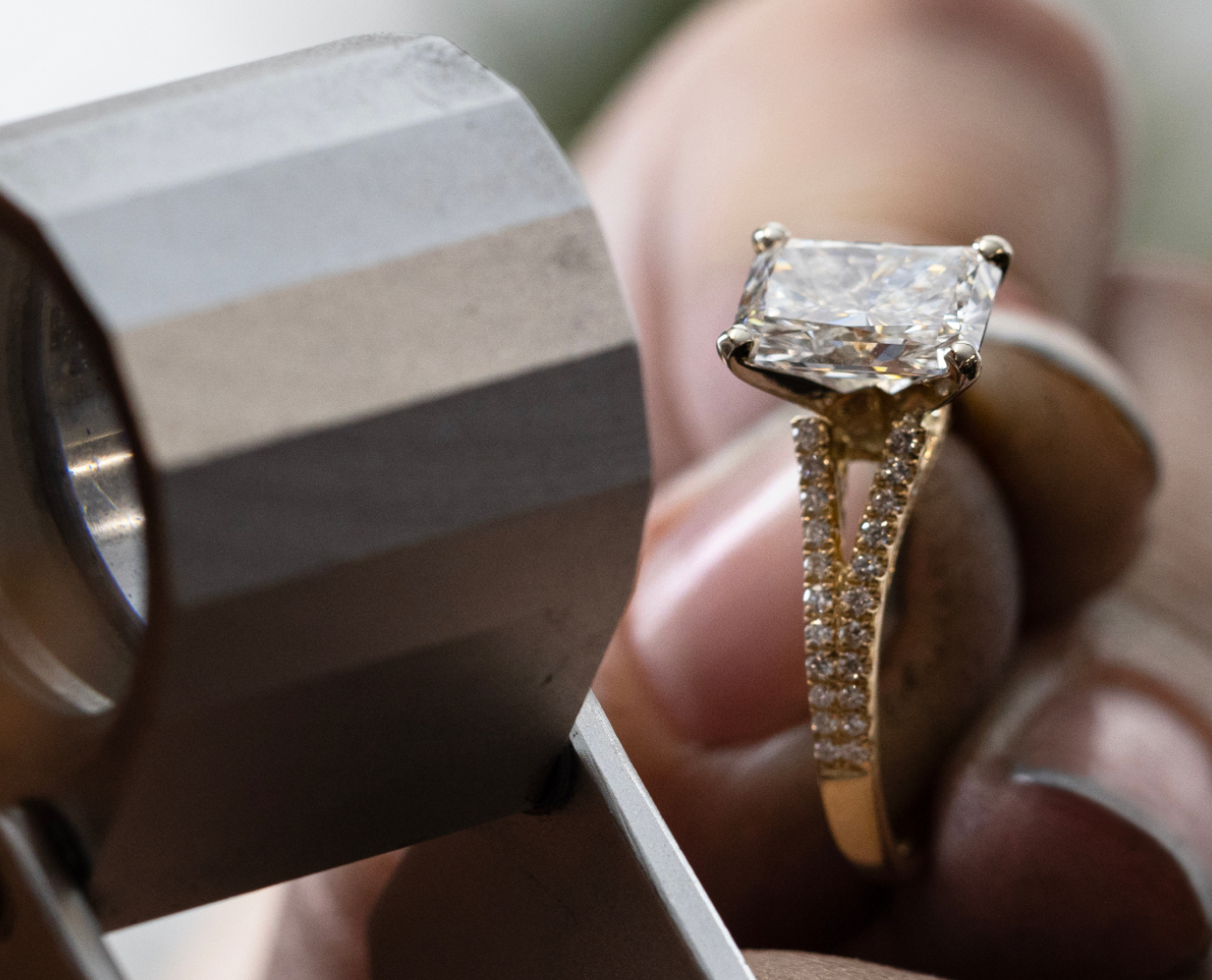 jeweler inspecting a gold engagement ring with a loupe