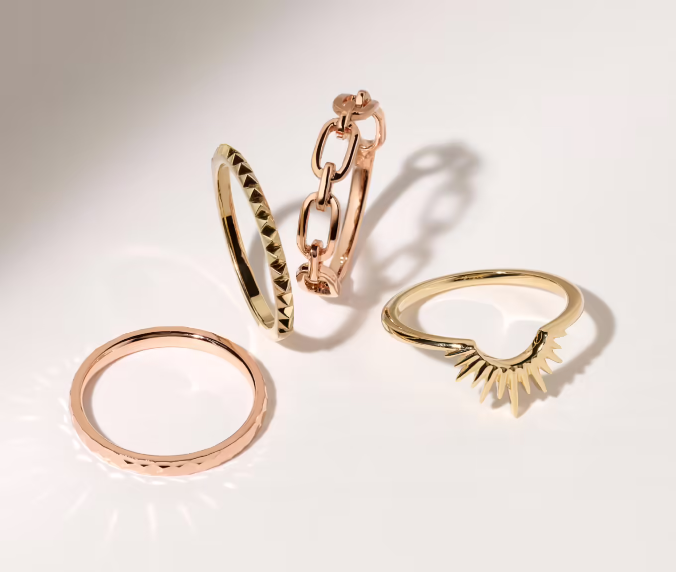 four gold wedding bands in varying styles. Riverbed 14K Rose Gold Band This 14-karat rose gold band offers unique texture and high shine with a stylish hammered finish. It’s beautiful next to an engagement ring or all on its own. 14k rose gold with hammered finish Approx. 2mm band width Engravable and resizable Martine Stackable 14K Yellow Gold Ring Whether worn alone or stacked with favorites, this 14-karat yellow gold ring will add style to any look with its studded texture. 14k yellow gold Stackable design Approx. 1.5mm band width Engravable and resizable Adria Link Ring in 14K Rose Gold Show-off your unique style with this lovely link ring. Our 14-karat rose gold has added alloys that make a bright and never-fading shade. Link design 14k rose gold 1.5mm band width Engravable and resizable Fringe Contour Wedding Band Accessorize one or both sides of another ring in style with this stunning contour wedding band. The 14-karat yellow gold has added copper, zinc, and silver alloys that produce a bright and never fading shade. • Classic contour design • Yellow gold • 1.5mm band width • Engravable and resizable