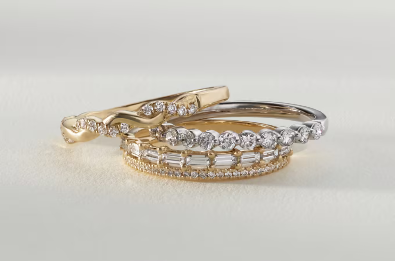 three stacked diamond rings. Willow Diamond Pave Infinity Band Like the winding branches of a willow tree, natural diamond pavé and warm 14-karat yellow gold twist into an infinity design in this beautiful band. 18 round natural diamonds at approx. 0.15 tcw Infinity design 14k yellow gold Approx. 2mm band width Engravable and resizable Terra 0.30 tcw Diamond Band The minimal single-prong setting of this ring showcases the gorgeous round shape and superior sparkle and fire of its natural diamonds. Crafted in bright 14-karat white gold, it makes a beautiful addition to any ring stack. 11 round natural diamonds at approx. 0.30 tcw 14k white gold Approx. 2mm band width Engravable and resizable Margaret Double Row Diamond Band This double-row design features one row of natural diamond pavé and second row of baguette natural diamonds in a nod back to the glamorous Art Deco era. Crafted in warm 14-karat yellow gold, it makes a beautiful wedding band or a great addition to any ring stack. 26 round natural diamonds at approx. 0.05 tcw 9 baguette natural diamonds at approx. 0.30 tcw 14k yellow gold Approx. 3mm band width Engravable and resizable