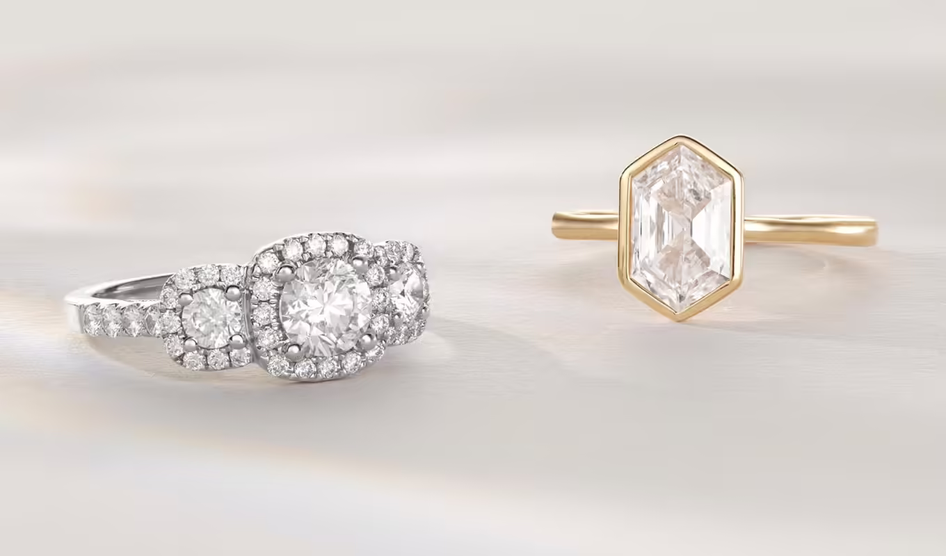 2 engagement rings. Collette 0.70 ct Diamond Engagement Ring (Round) Three halos turn up the sparkle of the classic three-stone design in this stunning engagement ring. Two main accents adorn the 0.70 ct. round natural center diamond while an ornate bejeweled profile lets it shine from every angle. Crafted in bright 14-karat white gold, all the natural diamonds in this dazzling ring are hand matched for consistent color, clarity, and sparkle. 1 round natural diamond center stone at approx. 0.70 ctw Clarity grade I1 & color range F-I 70 round natural diamond accents at approx. 0.85 tcw Halo design 14k white gold Approx. 2mm band width Engravable and resizable. 1 1/2 ct Lab-Grown Diamond Bezel Engagement Ring This stylish bezel-set engagement ring features a sparkling 1 1/2 ct. lab-grown diamond in a unique elongated hexagon cut. Crafted in warm 14-karat yellow gold, it has extra lab-grown diamond accents on the sides, so it sparkles from every angle. 1 elongated hexagon lab-grown diamond center stone at 1 1/2 ctw Clarity grade of VS2 Color range G-H 12 round lab-grown diamond accents at approx. 0.05 tcw 14k yellow gold Approx. 2mm band width Engravable and resizable.