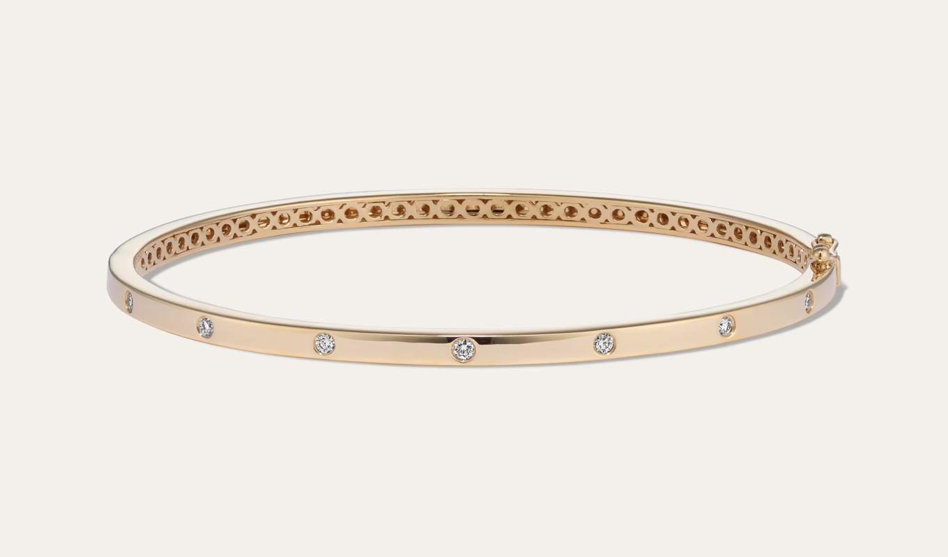 Diamond Bangle Bracelet Natural diamonds in a stylish flush setting dot this bangle bracelet with beautiful sparkle. Crafted in warm 14-karat yellow gold, it has a tongue clasp with a safety lock for extra security. It makes a special gift or a classic addition to your own jewelry collection. 7 round natural diamonds at approx. 0.15 tcw Hinged bangle design 7.5-inch length Approx. 3mm width Tongue clasp with safety lock 14k yellow gold