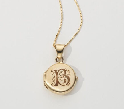 The image showcases a beautiful gold locket necklace. The necklace features a fine gold chain that supports a round locket pendant. Chain: The chain is delicate and made of gold, with a subtle link pattern that adds to the necklace's elegance and sophistication. Locket: The locket is round and made of gold, with a polished finish that gives it a classic and timeless appearance. The front of the locket is engraved with an ornate letter "B" surrounded by intricate scrollwork, adding a personalized and decorative touch. The locket is designed to open, allowing for the placement of small photos or mementos inside, making it a sentimental and meaningful piece of jewelry. The background is plain and light-colored, which helps to highlight the necklace and its details. The overall presentation emphasizes the craftsmanship and elegance of the locket, showcasing its potential as a cherished keepsake or a thoughtful gift. The design combines classic style with personal significance, making it a versatile and enduring accessory.