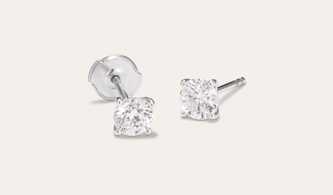1 tcw Natural Diamond Studs These classic stud earrings feature a pair of natural diamonds set in bright 14-karat white gold and hand-matched for consistent color, clarity, and sparkle. Each pair of diamonds is unique and may vary slightly from the images shown. They also feature a la pousette back with a convenient locking mechanism, designed to keep your earrings secure while still being comfortable. Just squeeze the side tabs, slide it to your preferred notch on the earring post, and let go to lock it in place. 2 round natural diamonds Minimum total carat weight of 1 carat Clarity grade of I2 Color range G-H 14k white gold La pousette back